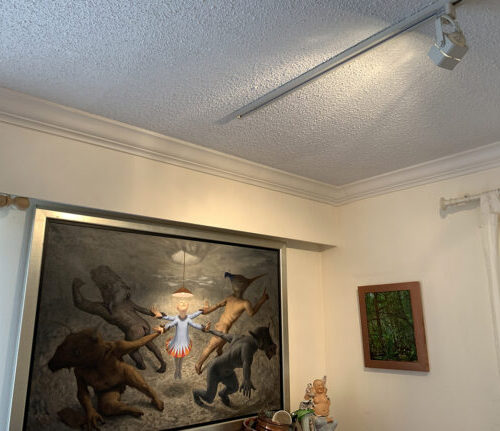 A single-track light is pointing directly at the highlighted figure in the center of the Michael Abraham painting, ‘My little God’
